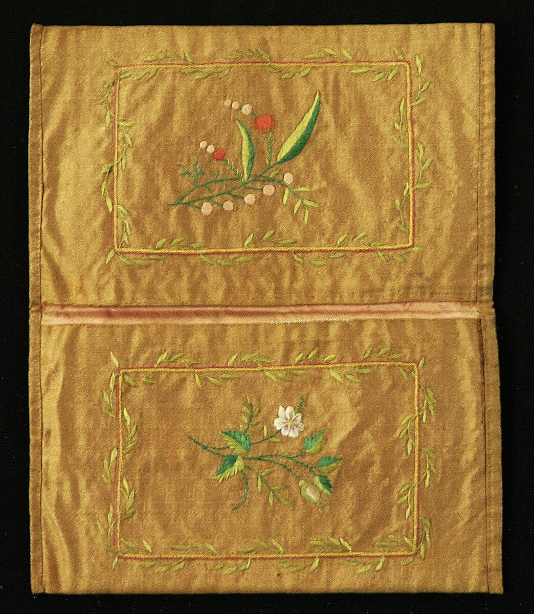 Sidenplånboken är av brungrönt tyg, modell bokomslag. Med broderier i flera färger både ut och invändigt, fodrad med rosa siden. På utsidan monogram "N R B"
På danska till L Ringbom och A C Mullde paa deras brullöpsdag 1766 i plånboksfodral af brunt sidentyg märkt N R B