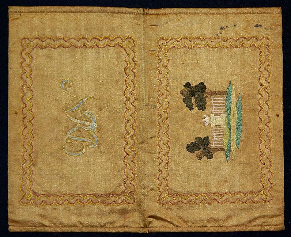 Sidenplånboken är av brungrönt tyg, modell bokomslag. Med broderier i flera färger både ut och invändigt, fodrad med rosa siden. På utsidan monogram "N R B"
På danska till L Ringbom och A C Mullde paa deras brullöpsdag 1766 i plånboksfodral af brunt sidentyg märkt N R B