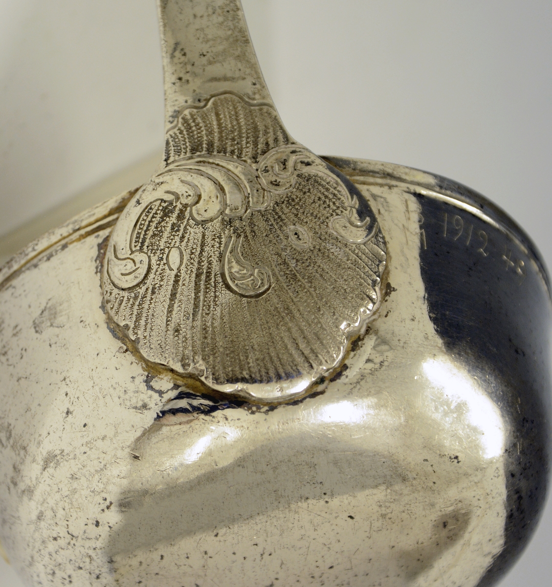 Sølv suppeøse. Dekorert med rokokko-ornamenter. Stemplet med København bystempel og ant. året 1779. (Tre tårn og 79), månedstempel for væren (20.03-20.04), guardeinstempel "F" ant. for Fredrik Fabricius ((1767)1787-1823, København) og mesterstempel PM.