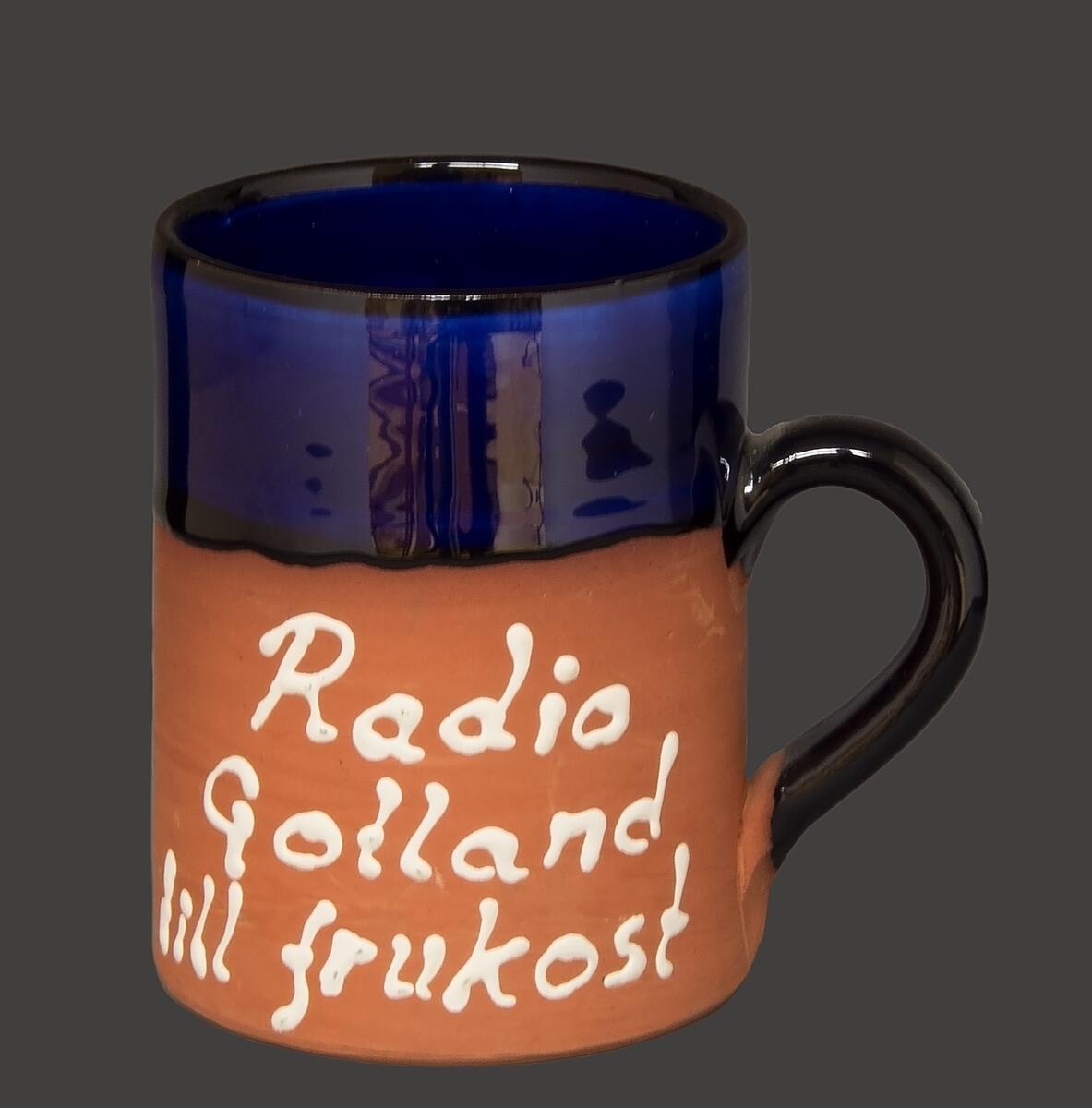 Två keramikmuggar tillverkade av gotlandskeramikern Agge Ahlin. Adresslapp finns ännu kvar på den ena koppen: "Tillv. Agge Ahlin, Förs. Strandg. 9, Visby". Godset är även signerat med AA Visby.

Muggarnas övre del samt muggens inre är glaserade i blått, örat är glaserat i svart. Mer än hälften av muggen är oglaserad men har en text skriven i vitt: "Radio Gotland till frukost".