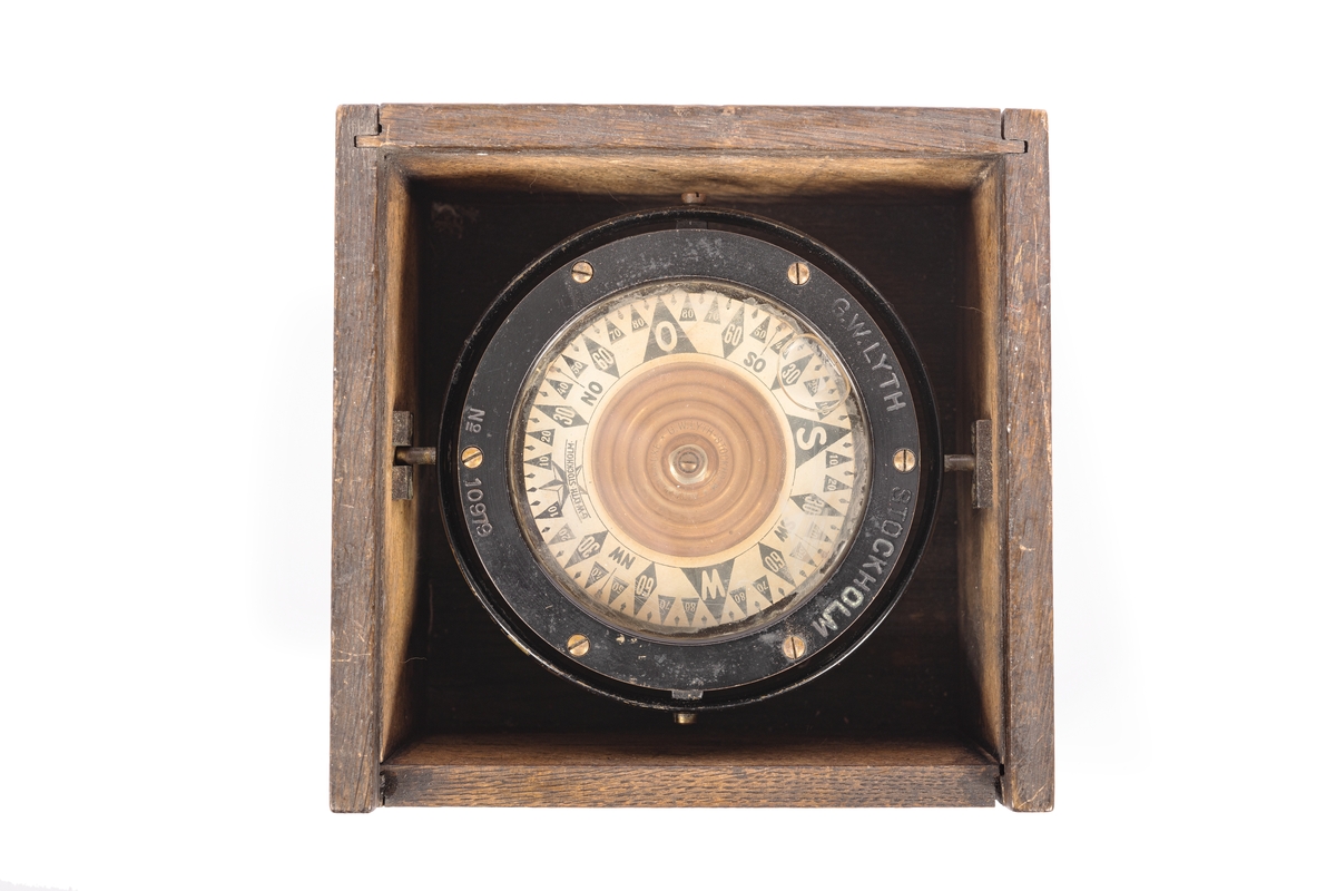 3,5 tums båtkompass, graderad i interkardinalstreck och 5 grader. Kardansk upphängning med röda tappar. Fyrkantig låda av ek med skjutlock.