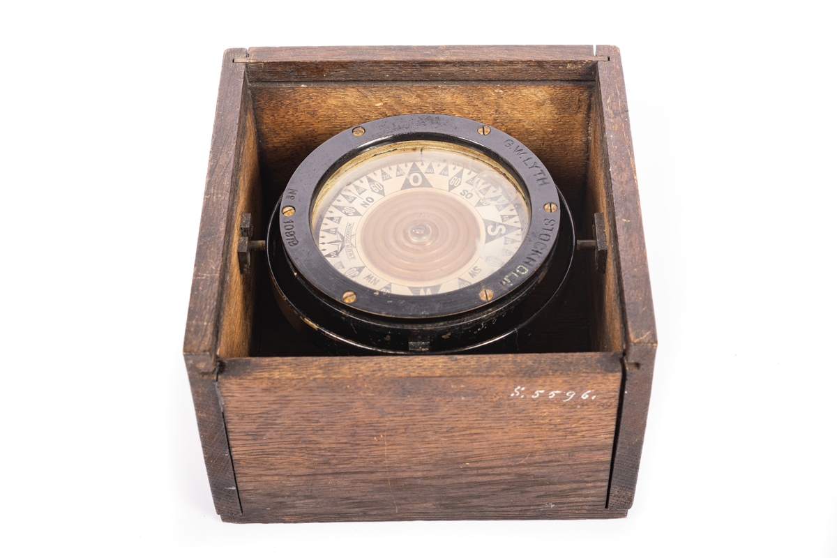 3,5 tums båtkompass, graderad i interkardinalstreck och 5 grader. Kardansk upphängning med röda tappar. Fyrkantig låda av ek med skjutlock.