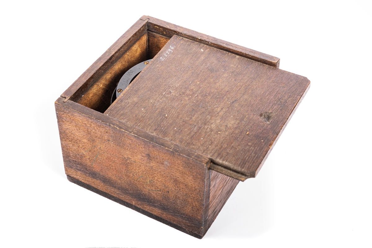 3,5 tums båtkompass, graderad i interkardinalstreck och 5 grader. Kardansk upphängning med röda tappar. Fyrkantig låda av ek med skjutlock.