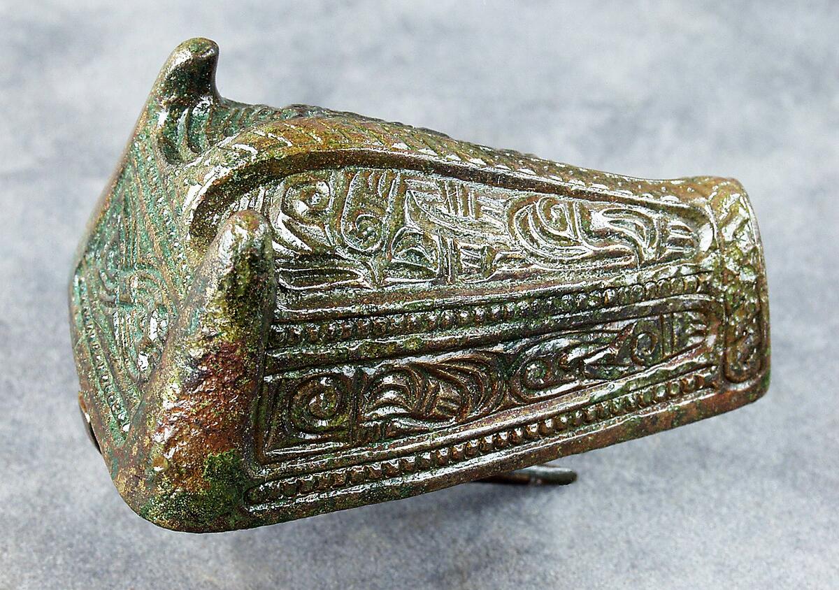 Djurhuvudformat spänne av brons, gjutet i ett stycke. Plan botten med nål. Ovansidan med huvudsakligen nonfigurativ ornamentik. Påträffat i grav 141/64 på kopparsviksgravfältet söder om visby.  Publ. Pettersson h 1966 (mälarstedt) undersökningen av gravfältet vid kopparsvik, gotländskt arkiv. Mälarstedt h 1979 kopparsvik- ett vikingatida gravfält vid visby. Arkeologi på gotland
nyreg 2002 ml