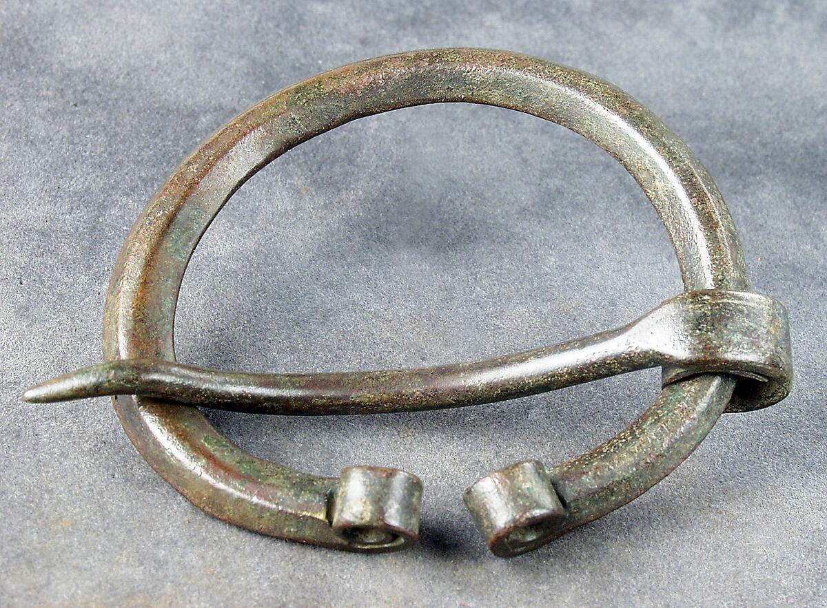 Ringspänne av brons av ten med spetsovalt tvärsnitt. Upprullade ändar typ 1a enl thunmark - nylén :die wikingerzeit gotlands. Påträffat i grav 143/64 på kopparsviksgravfältet söder om visby.  Publ. Pettersson h 1966 (mälarstedt) undersökningen av gravfältet vid kopparsvik, gotländskt arkiv. Mälarstedt h 1979 kopparsvik- ett vikingatida gravfält vid visby. Arkeologi på gotland.
nyreg 2002 ml
