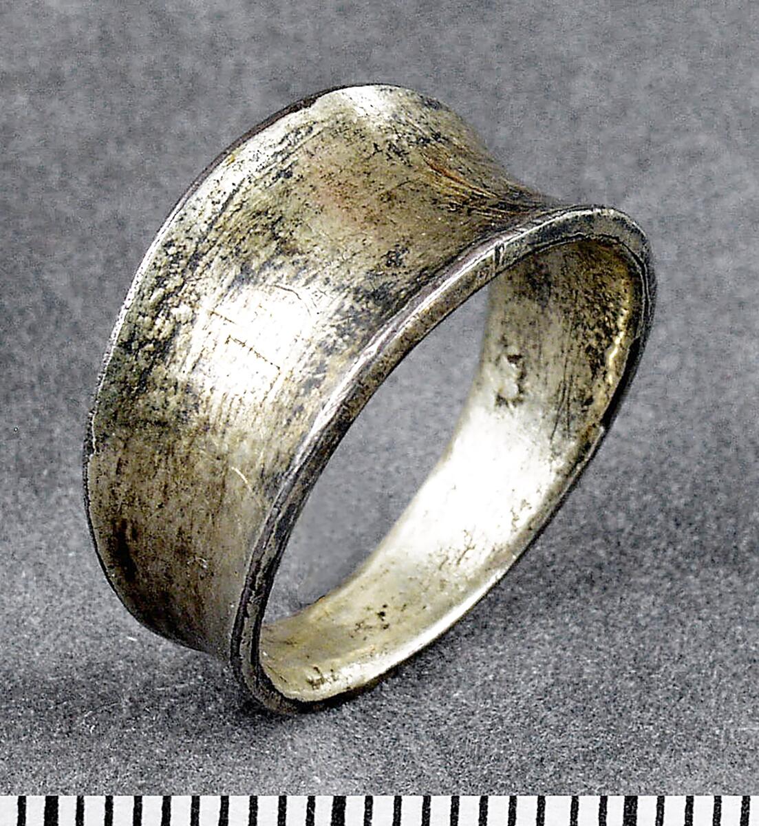 Fingerring av silver (?) med sliten förgyllning, sluten modell bredare på "framsidan" som är konkav
av silver, med nedsliten förgyllning, utan ornering, utsidan konkav. Diam. 2,2 cm.