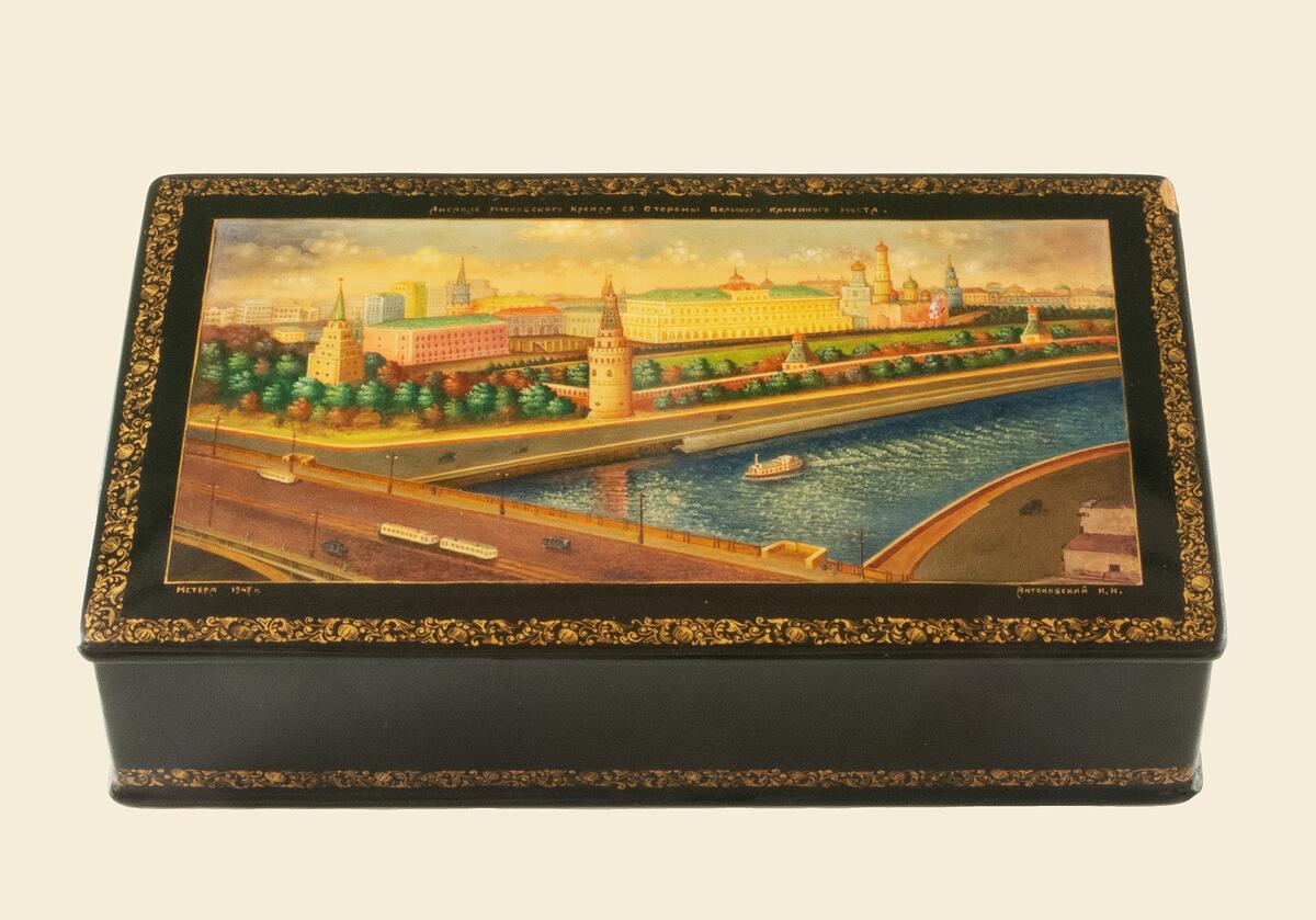 Träskrin med svartlackad utsida, lock på gångjärn, på locket en bild av stadsvy i flera färger, runt kanten guldbård, text på ryska i guld, troligen beskrivning av motivet  som troligen är moskva i modern tid, årtalet 1947 finns i vänstra hörnet, invändigt är skrinet rött föremålen c15844: - c15856: är inköpta i moskva på 1940-50-talet och kommer alla från samma donator, tekla jonsson född 1902, död 1994, gåvan förmedlad genom elsi wennman, bandhagen, elsi wennman ärvde tekla som själv hade hade bestämt att föremålen skulle skänkas till gotlands fornsal, tekla  kom som 6 mån baby till fosterföräldrar i burge i lummelunda, i gåvan ingår även en gotlandsdräkt, c 15857:  handlingar rörande fosterhemsplaceringen, c15858: samt två förkläden c15859: - c15860:. Nyreg data 021107 li