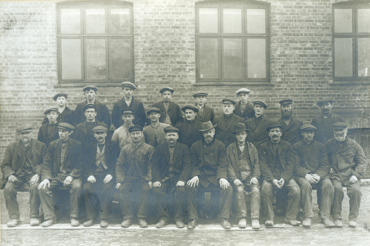 Arbeidsmannskap ved Helly J. Hanseni Moss 1914.

1. Per Pedersen ("Skjeltet"), utv. avd.  (far av Emanuel).
2. Ludvig Karlsen (smøreavd.)
3. Petter Christensen, formann smøreavd. 
4. Carl Johansen, formann utv. avd. 
5. Martin Halvorsen, formann pakkeriet. 
6. Thorvald Olsen, formann klipperiet (far av Thormod).
7. Maler Ole Andersen ("Maler'n")
8. Marius Gulliksen, formann i fjærfabrikken
9. Emil
10. Grefer Hauge ("Gress"), snekker. 
11. Anders Wilhelmsen, pakkeriet. 
13. Josef Andersen ("Sover'n"), smører. 
14. Paulsen, pakkeriet.
15. Frithjof Halvorsen, smører.
16. Aksel Kristiansen, smører.
17. Johannes Andersen, smører. 
18. Lars Karlstad, snekker. 
19. Aksel Edstrøm ("A.. utydelig) maskinist.
20. Reidar Svendsen ("Ke...utydelig"), smøreavd. 
21. Hen.... Larsen ("Loppen"), smører.
22. Oscar Hansen, ("Sjakken"), smører. 
23. Hjalmar Skog, klipperiet. 
24. Olsen, smører. 
25. Hans Solberg.
Plassering av personenene på bilet er ikke angitt, antakelig starter man med bakerste rekke.