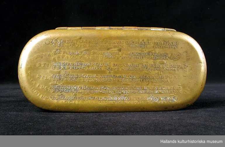 Kalenderdosa. Rektangulär med rundade hörn. På locket en kalender med bokstäver och symboler i upphöjd relief. Höger: "FORSWENSKAD 1787 4/1". Vänster: "JANUAR: FEBRUA: MARTI: APRIL: MAIUS: JUNIUS:" Mittbak på dosans kant finns ett hål.