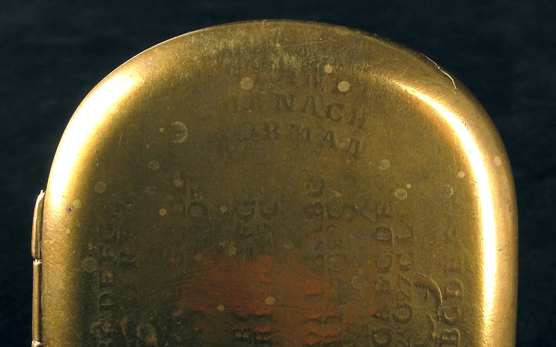 Kalenderdosa. Rektangulär med avrundade hörn och fällock. På locket en kalender med bokstäver och symboler i upphöjd relief.