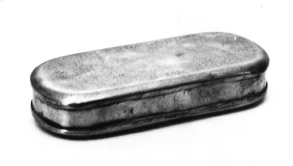 Kalenderdosa. Rektangulär med avrundade hörn och fällock. På locket en kalender med bokstäver och symboler i upphöjd relief.
