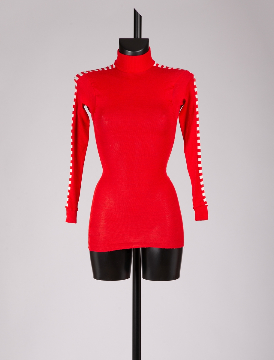 Art. nr. 46036. Rød trøye med røde og hvite skråstilte striper på ermene. Stripene er varemerkeregistrert på Helly Hansen. Høy hals og påsydde, ribbestrikkede mansjetter nederst på ermene. 
Art. nr. 46008. Rød bukse med røde og hvite skråstilte striper ned langs føttene. Stripene er varemerkeregistrert på Helly Hansen. Elastikk i livet. Påsydd rib på ben.