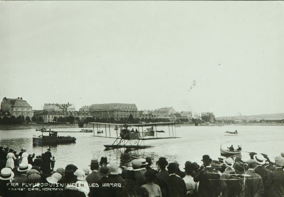 Postkort, Hamar, flyoppvisning i Hamarbukta, en dobbeldekker N-6 Friedrichshafen FF.49, registrert 1920 eller 1921, flyet var i Tancred Ibsens eie, gjennom firmaet A/S Aero, tilskuere 
