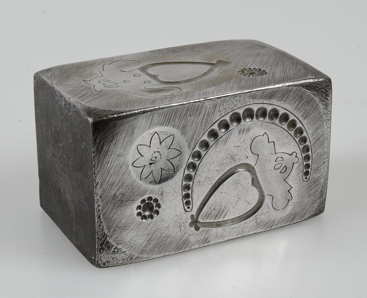 Rektangulär stans av järn till allmogebrosch. Har stansar på två sidor, till två olika broschmodeller.