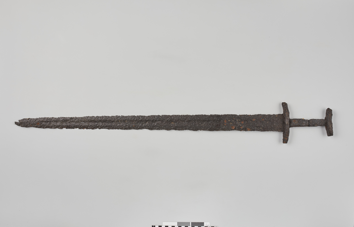 Sverd av jern fra vikingetiden, som Jan Petersen: Vikingsverd, type Q. En del forrustet, men stort sett bra bevart med tydelig blodrefill på klingen. St. lengde ca. 0,97 m, klingens st. bredde 5,9 cm, underhjaltets lengde 12,7 cm.