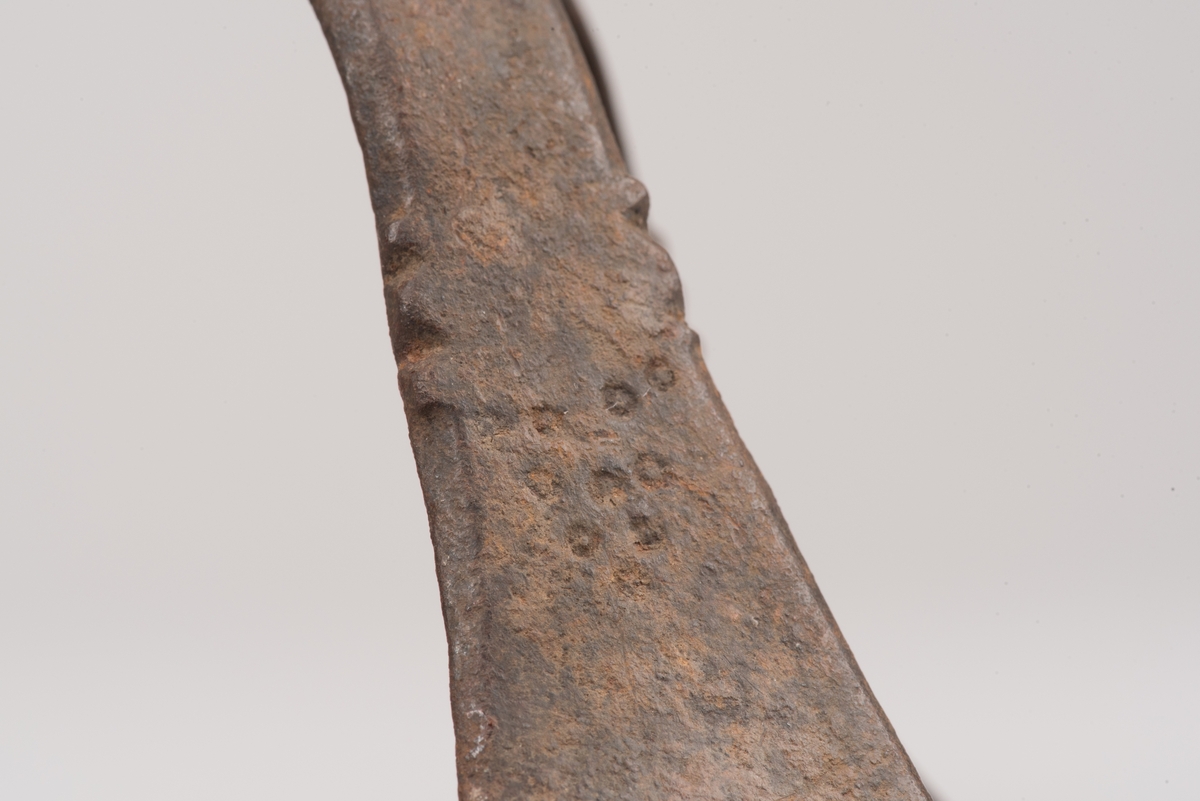 Ljusstake av järnplåt.
Ljusstake med tre fötter som har en uppvikt kant nederst och är avsmalnande uppåt. Fötterna är fästade vid en rund platta där även den smala ljuspipan sitter.
Fötterna är dekorerade med grunt inslagna cirklar som bildar en triangel med spetsarna nedåt. Kanterna är avfasade och ovanför trianglarna är kanten även markerad med några skåror.