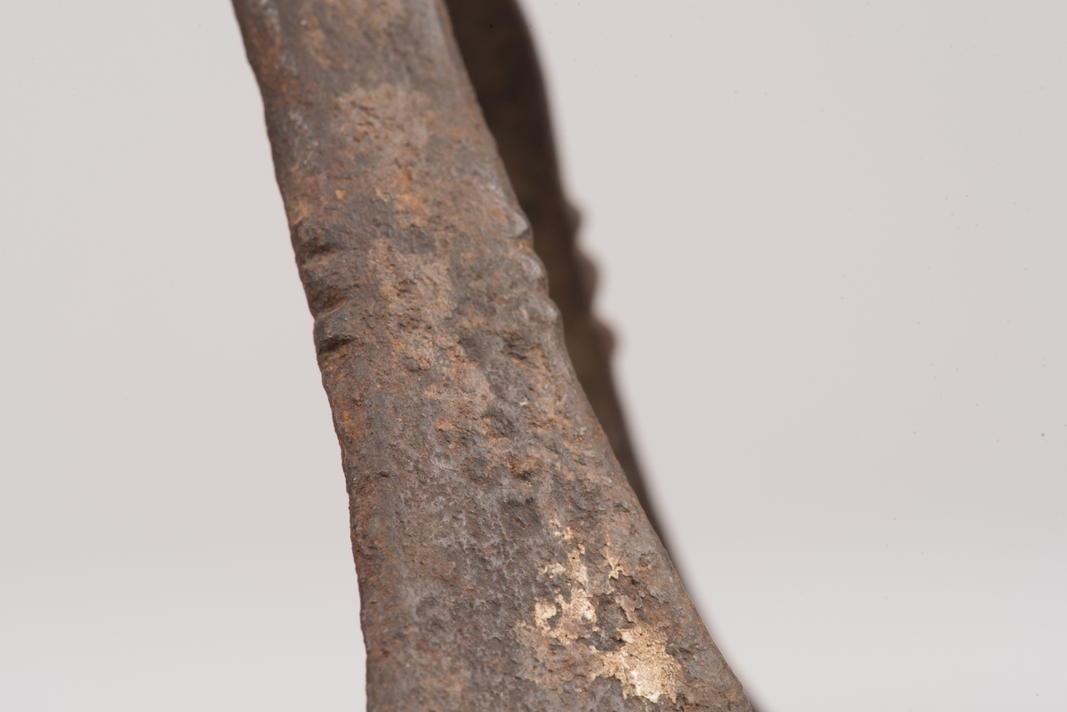 Ljusstake av järnplåt.
Ljusstake med tre fötter som har en uppvikt kant nederst och är avsmalnande uppåt. Fötterna är fästade vid en rund platta där även den smala ljuspipan sitter.
Fötterna är dekorerade med grunt inslagna cirklar som bildar en triangel med spetsarna nedåt. Kanterna är avfasade och ovanför trianglarna är kanten även markerad med några skåror.