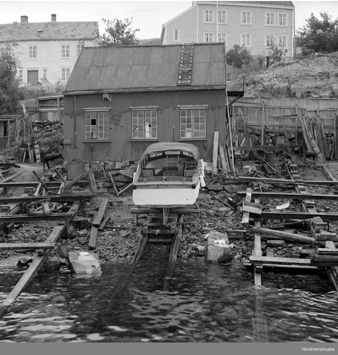 Foto fra en båt på slipp med et eldre hus i bakgrunnen. Bildet er merket Øverland. Fra fotoarkivet etter portrettfotograf Claus Monge. Nordmøre museum overtok samlingen fra sommeren 2011.