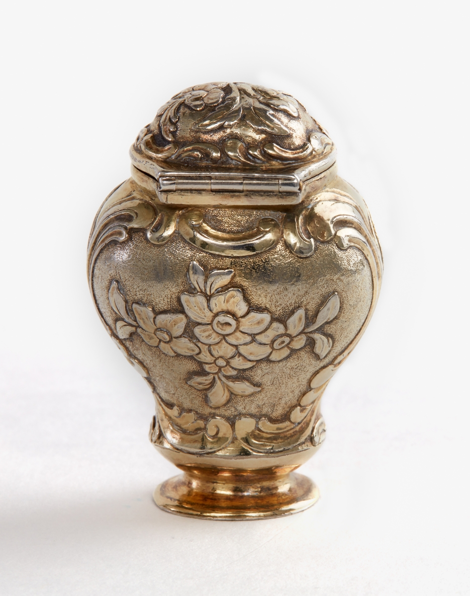 Dosa, luktdosa av förgyllt silver. Rokoko, tillverkad 1764. Bukig med ledat lock. Avsmalnande mot liten fot. Blomornament över hela dosan. Stämplad: "Falustadsstämpel, OHS, F". OHS=Otto Henrik Sjöberg, F=1764.