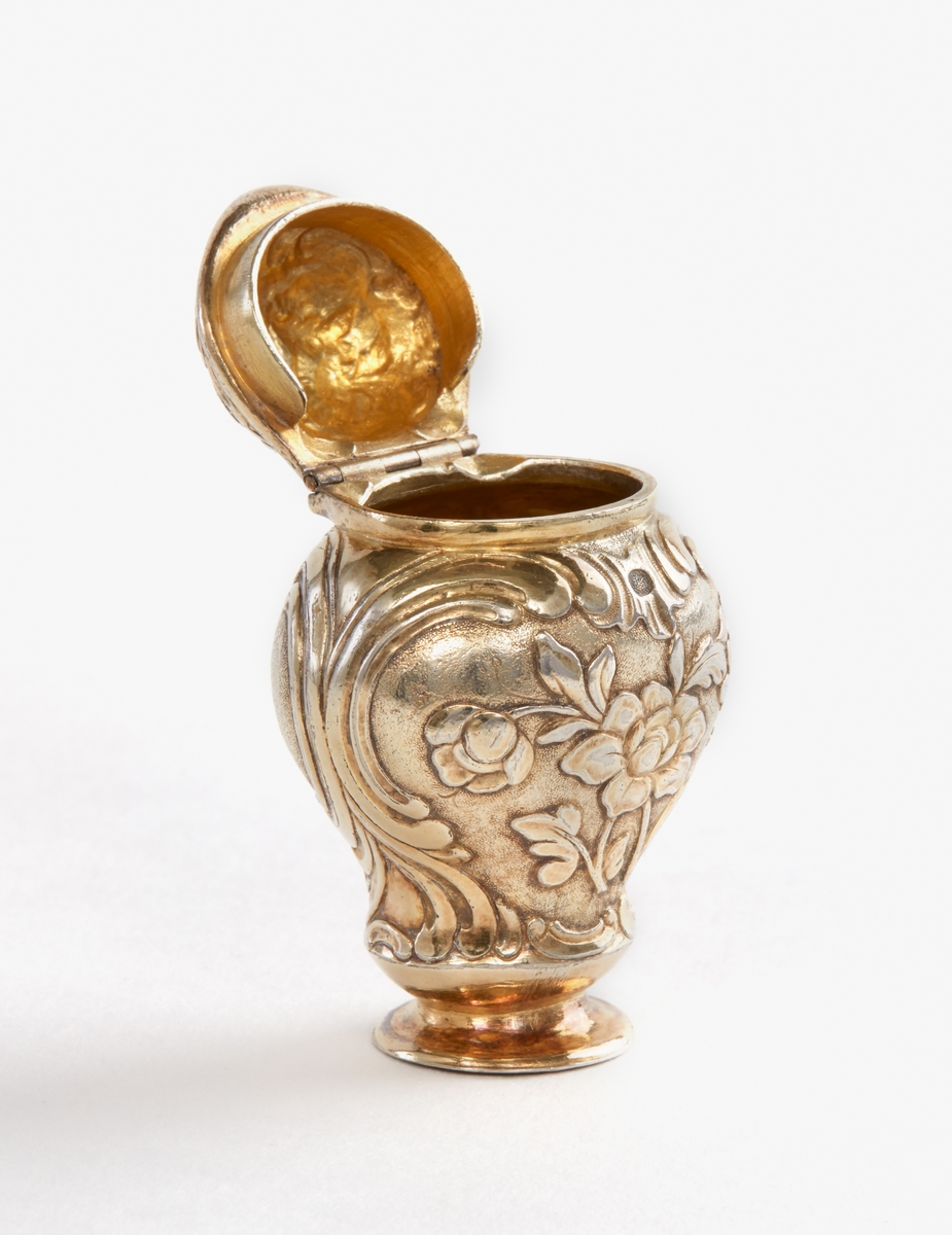 Dosa, luktdosa av förgyllt silver. Rokoko, tillverkad 1764. Bukig med ledat lock. Avsmalnande mot liten fot. Blomornament över hela dosan. Stämplad: "Falustadsstämpel, OHS, F". OHS=Otto Henrik Sjöberg, F=1764.