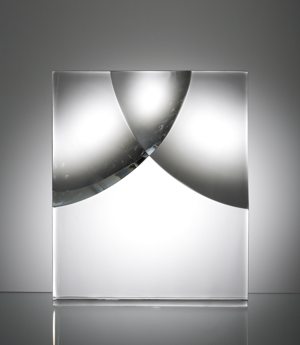 Formgivare: Sven Palmqvist. Glasskulptur, stående rätblocksform. Utförd med slipad konkav yta i främre och bakre vägg.