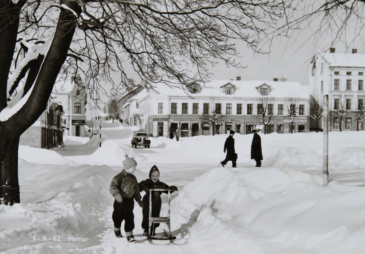 Postkort, Hamar by, Stortorget, Strandgata, vinter, barn med sparkstøtting, Aasgården i bakgrunnen med Kafe Nor,