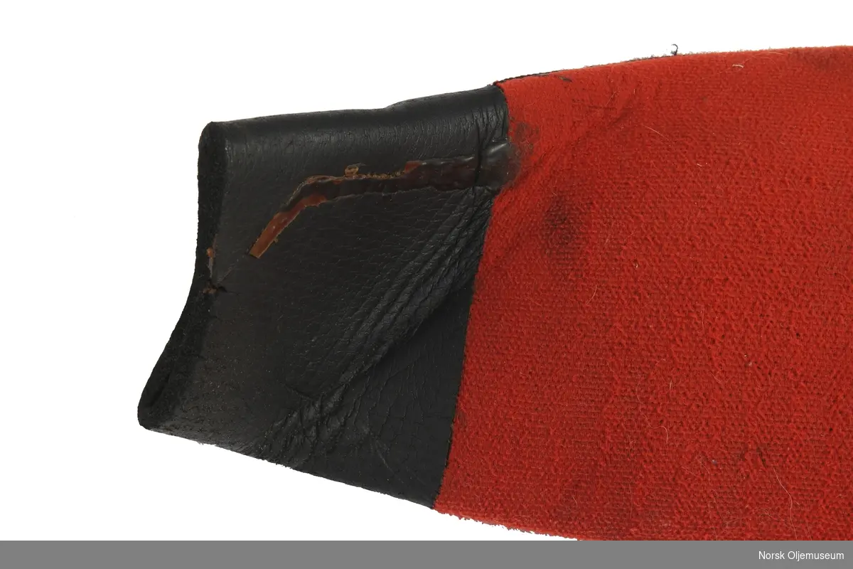 Tørrdrakt av neopren. Dykkerdrakten er av merke Poseidon og det er utført reparasjoner og endringer på drakten. Den har påsatte svarte sko som ikke er originale og utventil er plassert øverst på venstre arm. Foran på brystet har den to påsydde runde lapper av neopren. Drakten har slitasje på knærne fra bruk.