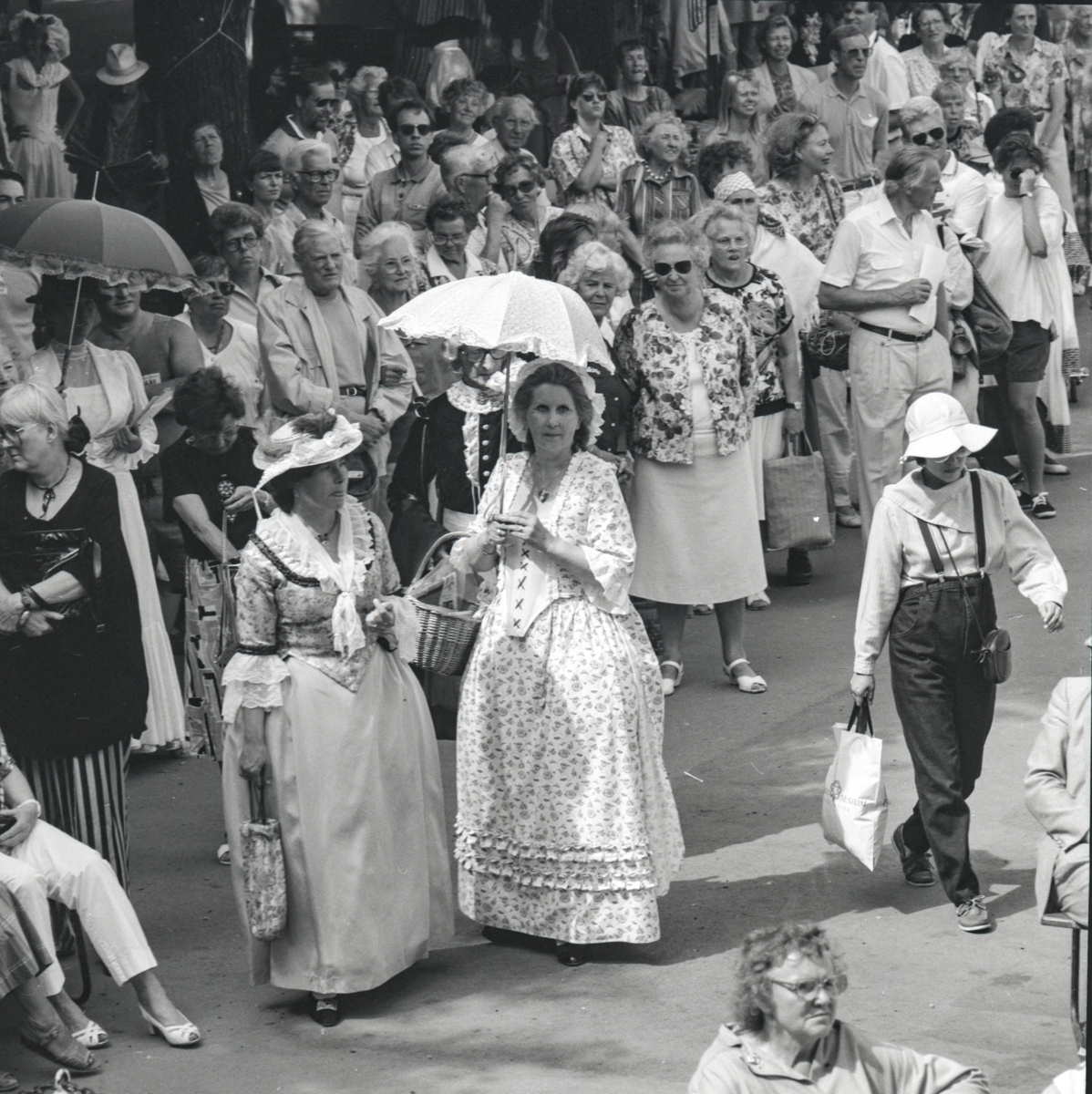 Utställningsverksamhet, "Vår roliga historia". Två damer i historiska dräkter vandrar bland publiken.