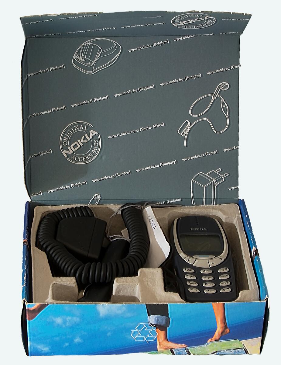 Nokia mobiltelefon modell 3310. Skal av mörkblått plast med silverfärgade knappar och rektangulär display. I originalkartong med laddare, billaddare, instruktionsbok och inköpskvitto.
