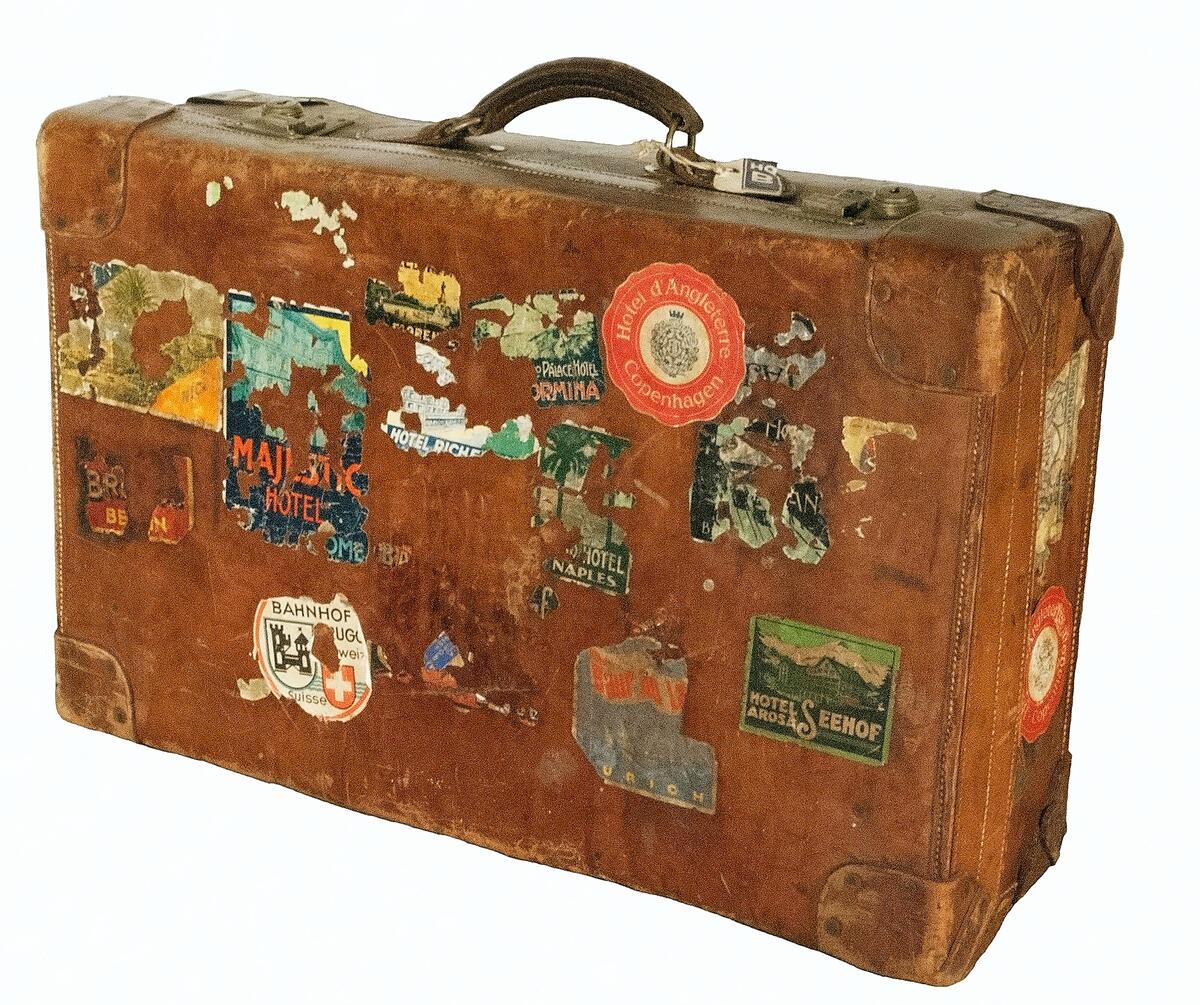 Väska, resväska. Cognacsfärgat läder med detaljer i mässing. Rektangulär form med ett handtag och två lås. Initialerna "E.R." (Ellen Roosval) inpressade på lockets ovansida. Svart insida med två fästremmar i läder. Lockets insida märkt med "John Pound & Co. Ltd. Actual Makers 265-270, Oxford St. 67 Picadilly, 187 Regent St. 81-84, Leadenhall St. London" i förgylld inramning. Ovansida och sidor med fraktetiketter samt klistermärken från besökta hotell, båtfärder med mera.
Nyreg 20130219 JE