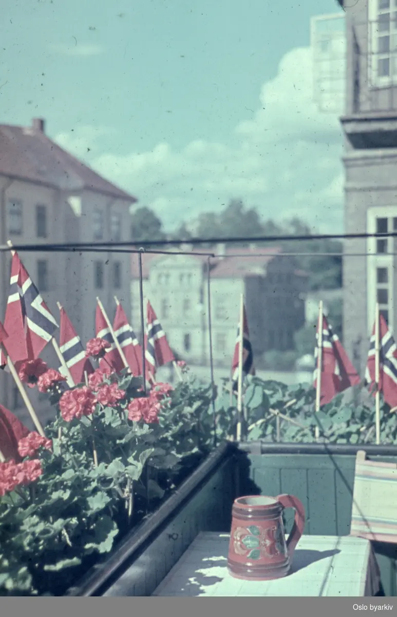 Balkong pyntet med blomster og flagg under feiringen av frigjøringsdagene 1945.