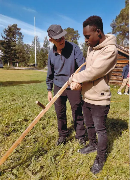 Egil Simensen med innvandrer som skal lære seg å slå med ljå