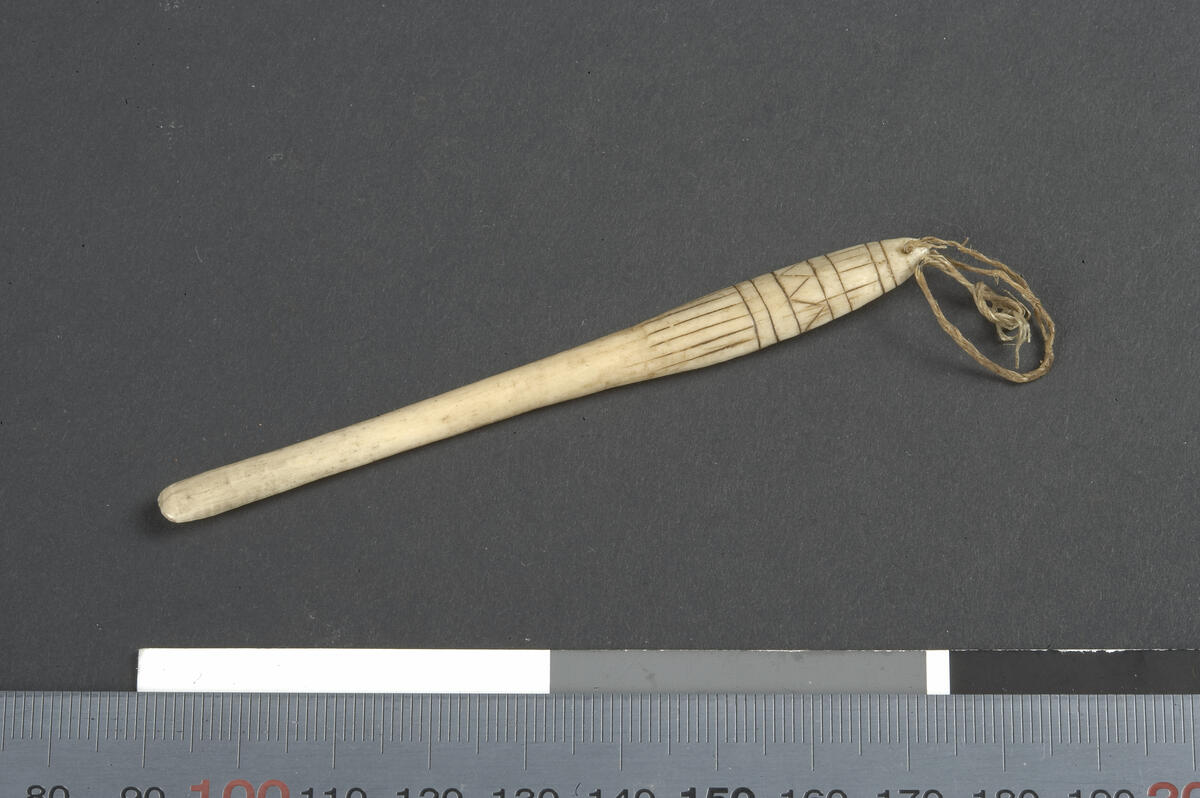 Fra hovedkatalogen: Redskab af ben eller rensdyrhorn, med bredt afrundet spids, muligens anvendt som rynkeben. Kong Williams land. <ENG>From the Accessions catalogue: Bone spatula /Redskab,with a broad, rounded tip, possibly used as a rynkeben (tool for working hide).Length 8.8 cm. King William Land.</ENG><IKU>ᐊᑐᐃᓇᐅᑎᑦᑎᔾᔪᑕᐃ’ᓂᑦ ᑎᑎᕋᖁᑕᐃ’ᓂᑦ: ᓴᐅᓂᖅ ᐃᓚᐅᑦ/ᐊᒡᓗᒧᑦ,  ᓯᓕᒡᑐᖅ, ᐊᒡᒪᓗᑑ’ᓗᓂ, ᐊᑐᖅᑕᐅᕙᒡᑐᒡᓴᐅᔪᖅ ᓴᓇᕐᕈᑕᐅ’ᓗᓂ.  ᑕᑭᓂᖃᖅᑐᖅ 8.8 cm. ᕿᑭᖅᑕᒥ. <anm>VIII, 12.</anm> </IKU><FRA>Du registre des acquisitions: Spatule en os, avec une pointe large et arrondie, possiblement utilisée comme outil pour étirer la peau. Longueur 8,8 cm. Île du Roi-Guillaume <anm>VIII, 12.</anm> </FRA>