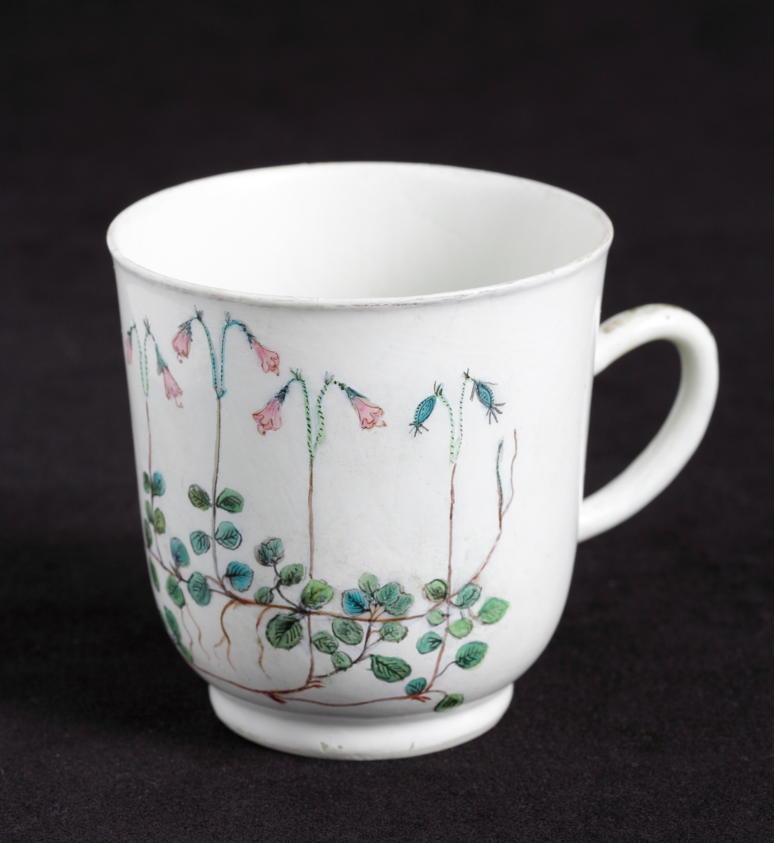 Kaffekopp med dekor av blommande linnéor i rosa och gröna nyanser runt om. 
Tillhörande tefat finns.

Inskrivet i huvudkatalog 1935.