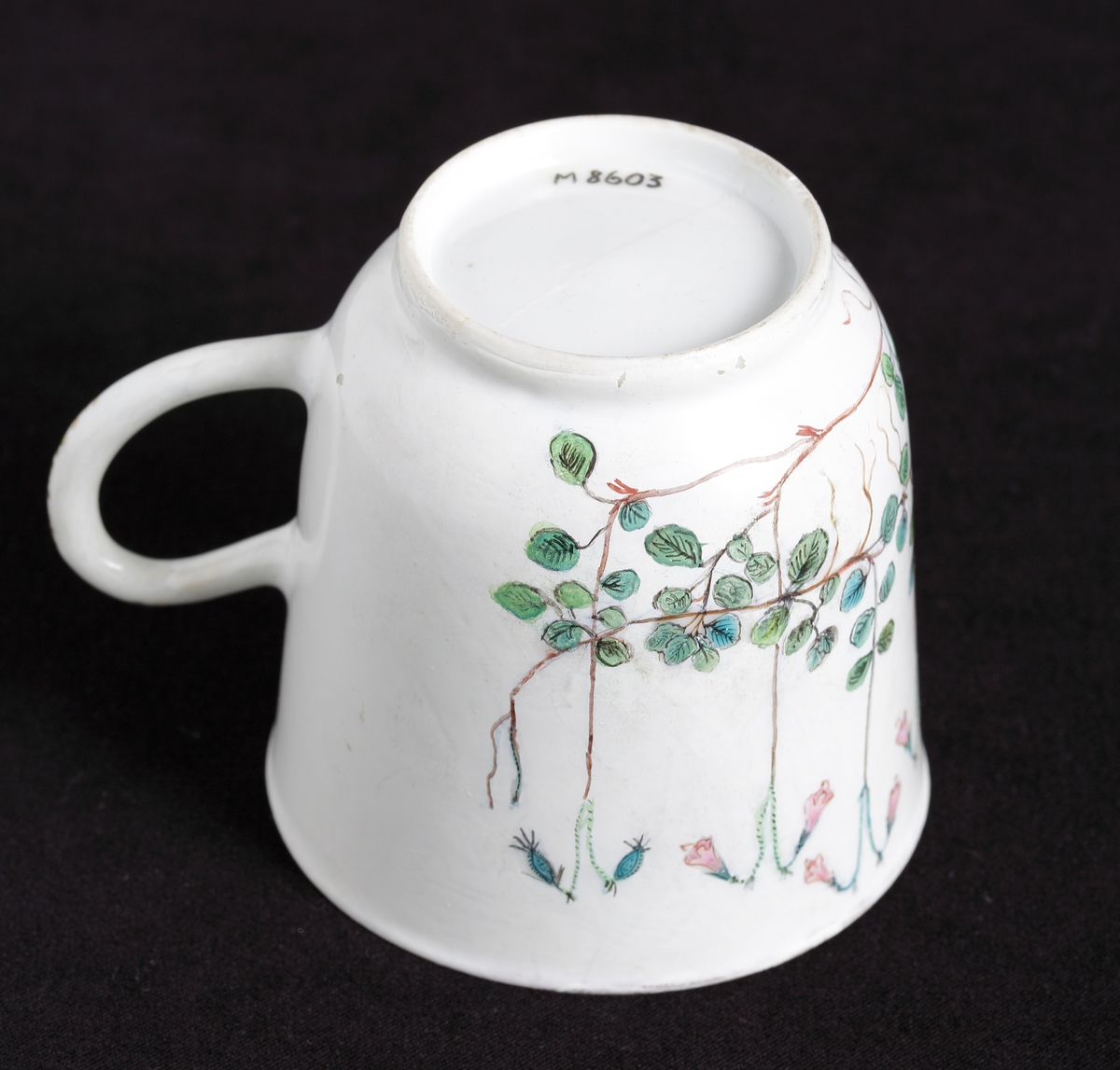 Kaffekopp med dekor av blommande linnéor i rosa och gröna nyanser runt om.
Tillhörande tefat finns.

Inskrivet i huvudkatalog 1935.