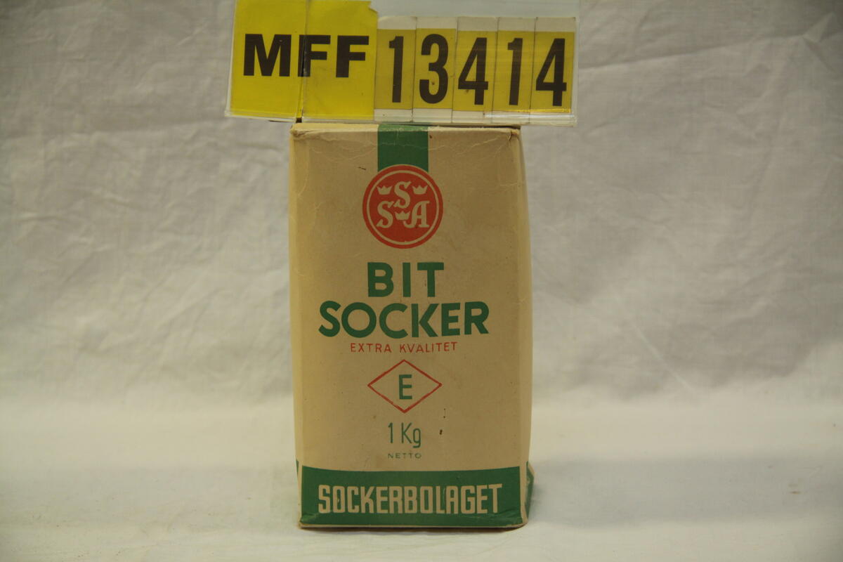 SSA. Bitsocker Extra kvalitet. 1 kg netto. Sockerbolaget. Grönt tryck. "Socker är ett billigt, rent och näringsrikt födoämne".