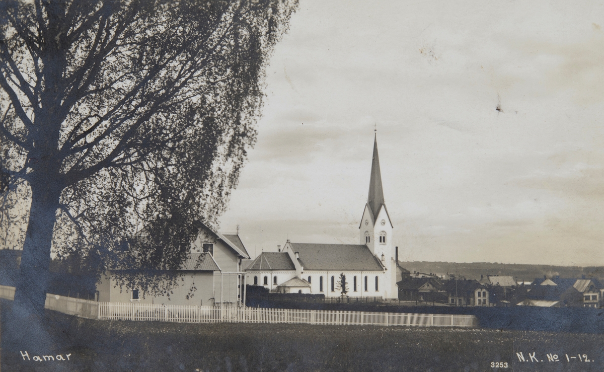 Postkort, Hamar, Kirkegata 14 Hamar domkirke sett fra Sagatunjordet, i forgrunnen A. Sæthers villa i Kyhns gate, bjørka sto på tomta til Lars Larsen,
