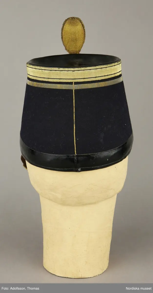 Huvudliggaren:
"Hatt, Kepi m.m.
Tillhört Stockholms borgerskaps infanteri-uniform.
a) Trekantig hatt med plym.
b) Kepi. Märkt: [avtecknat C i dubbelmonogram och XV] med plym.
c) Epåletter märkta: FYRWALD".
d) Huggvärja. Fäste af mässing, med bygel, parerstång och parerplåt, skaften lindad med silfvertråd, knappen urnformig, upptill med platta, för sigill; klingan eneggad och prydd med vapentrofeer m.m. i etsning.
e) 24 knappar.
G. af skomakaren C. A. Hedman i Stockholm. 29/5 1883."