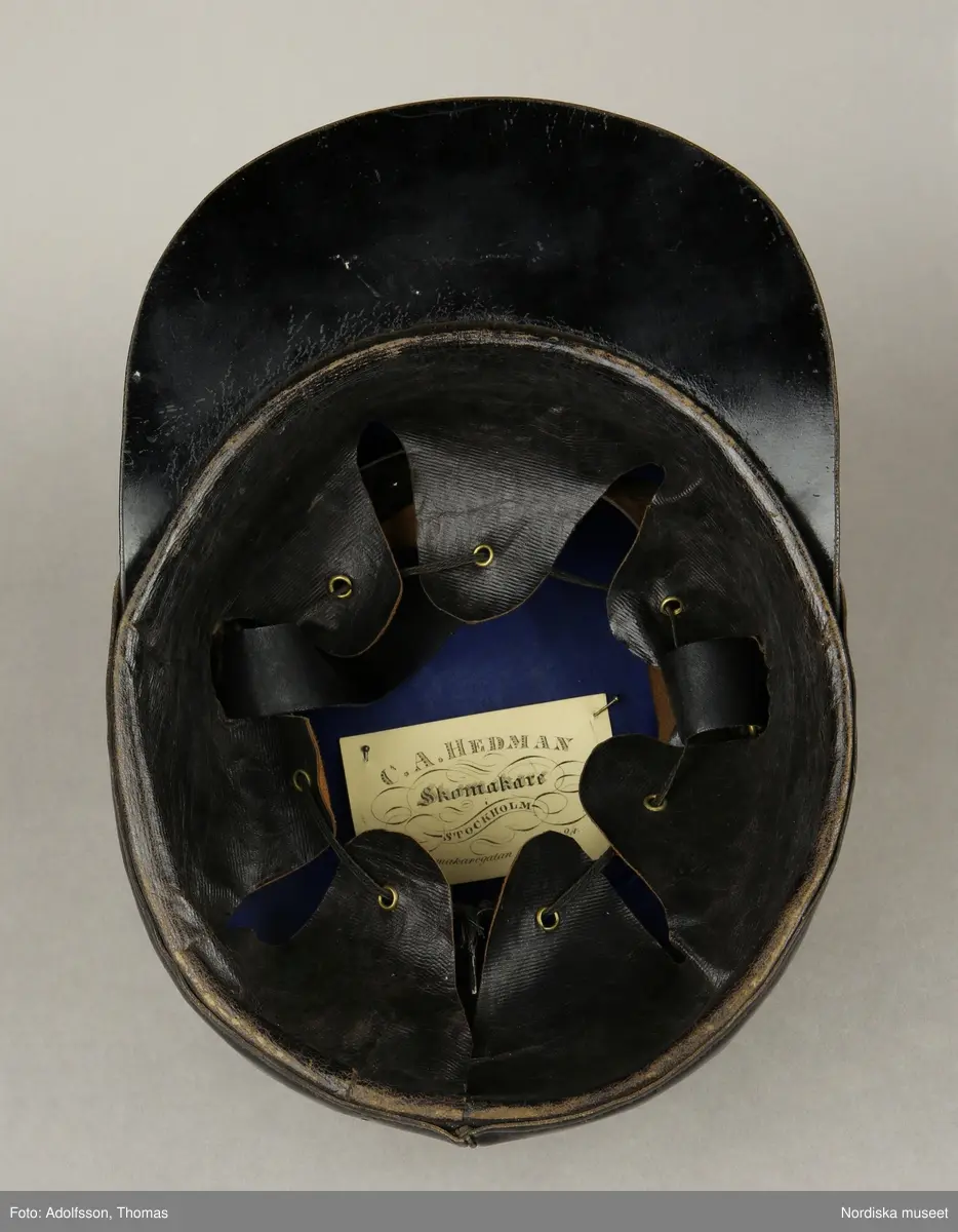 Huvudliggaren:
"Hatt, Kepi m.m.
Tillhört Stockholms borgerskaps infanteri-uniform.
a) Trekantig hatt med plym.
b) Kepi. Märkt: [avtecknat C i dubbelmonogram och XV] med plym.
c) Epåletter märkta: FYRWALD".
d) Huggvärja. Fäste af mässing, med bygel, parerstång och parerplåt, skaften lindad med silfvertråd, knappen urnformig, upptill med platta, för sigill; klingan eneggad och prydd med vapentrofeer m.m. i etsning.
e) 24 knappar.
G. af skomakaren C. A. Hedman i Stockholm. 29/5 1883."