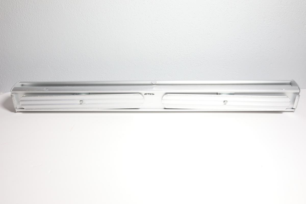 Rollup med med etui, har en stang bak til å holde den oppe. Den har informasjon på engelsk om å bruke maske og holde en meter avstand for å stoppe covid-19. Enkelt bilde av kvinnehodet med ansiktsmaske i mellom tittelen og informasjonen. I bunnen logo til Helsedirektoratet og FHI. Det er teipet over noe tekst i mellom informasjonen og logoene.