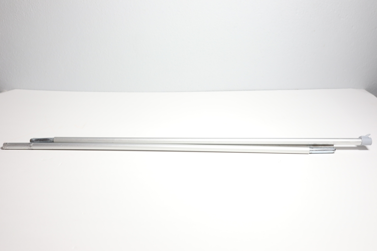 Rollup med med etui, har en stang bak til å holde den oppe. Den har informasjon på engelsk om å bruke maske og holde en meter avstand for å stoppe covid-19. Enkelt bilde av kvinnehodet med ansiktsmaske i mellom tittelen og informasjonen. I bunnen logo til Helsedirektoratet og FHI. Det er teipet over noe tekst i mellom informasjonen og logoene.