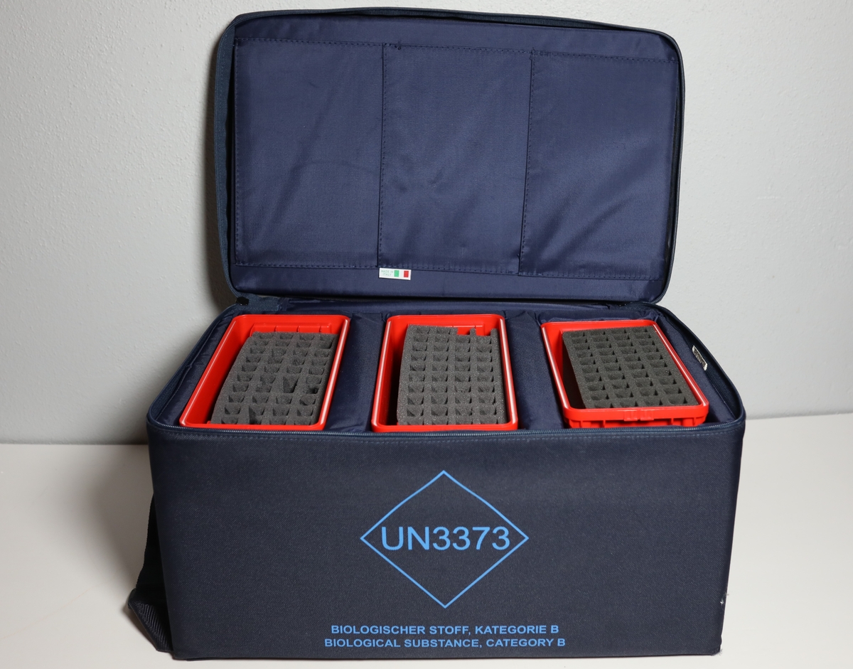 Bag med rom til tre bokser "Vacuette Transport Box" som det ble fraktet Covid-tester i. Glidlås rundt toppen av bagen. Den har håntak i midten av toppen, og på kortside er det feste for strop som man kan bære bagen med. På baksiden er det plastlomme med informasjon. Boksene har gjennomsiktige lokk, og har skumformer i til å plassere opp til 40 testrør i.