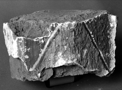 Valvribba. Tegelfragment med kalkmålning. Målad puts på två ytor: Sida, 18 x 10 cm. Röd spets omgiven av bruna fält. Underdel, 6 x 5 cm. Ljusgrönt fält.
