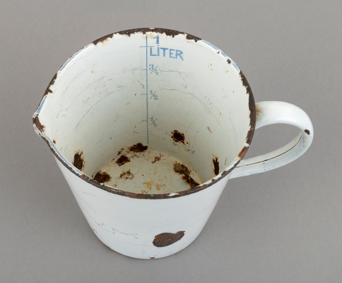 Målebeger, brukt ved tilberedning av matretter der man arbeidet etter oppskrift som forutsatte innblanding av ulike volumer av ymse ingredienser. Dette begeret er lagd av jernblikk som er emaljert. Det er formet som et digert krus, rundt, men noe smalere i botnen enn i munningen. Begeret er 13 centimeter høyt. Ved standflata er diameteren snaut 9,5 centimeter, i den øvre enden 12,9 centimeter. Det sistnevnte målet omfatter ikke et lite «nebb» i fronten, diametralt overfor handtaksbøyla, som er lagd av en blikkstrimmel som er formet slik at den er blitt til et rør med ovalt tverrsnitt, med unntak av ytterendene, som er flattrykte. Disse er sveiset på begerets yttervegg. Overflatene har vært dekt av kvit emalje, men begeret later til å ha fått en del støt, som har blottlagt underliggende jern, som framstår som rustflekker. Inni begeret er det ei blåfarget vertikal linje med tverrstreker som markere 1/4, 1/2, 3/4 og 1 liter,