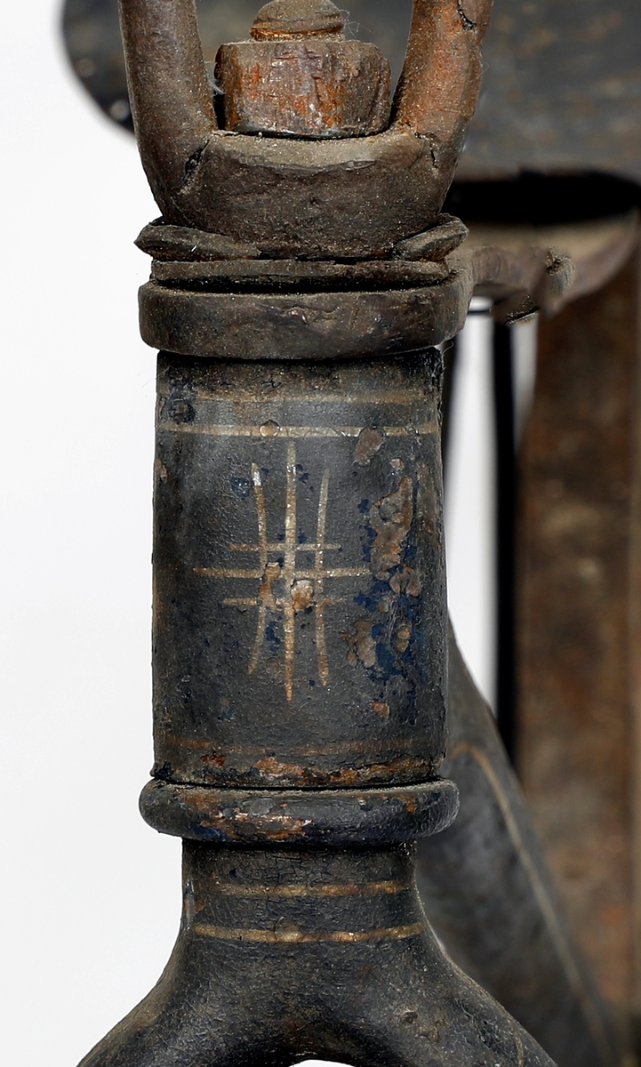 Sykkel av jern med hjul i tre med jernbånd/skoning ytterst. Hjulene har ulik størrelse, størst foran, kan ha vært kjerrehjul en gang, men er laget i smekre materialer. Bemalt i beige med kremhvite linjer, mulig rødt under? Jernrammen er svart, med rester etter dekorasjon i form av linjer. Pedaler på framhjulet (samme system som velte-petter). Trehåndtak. Setet har små huller ytterst som kan ha vært feste for polstring/lær.