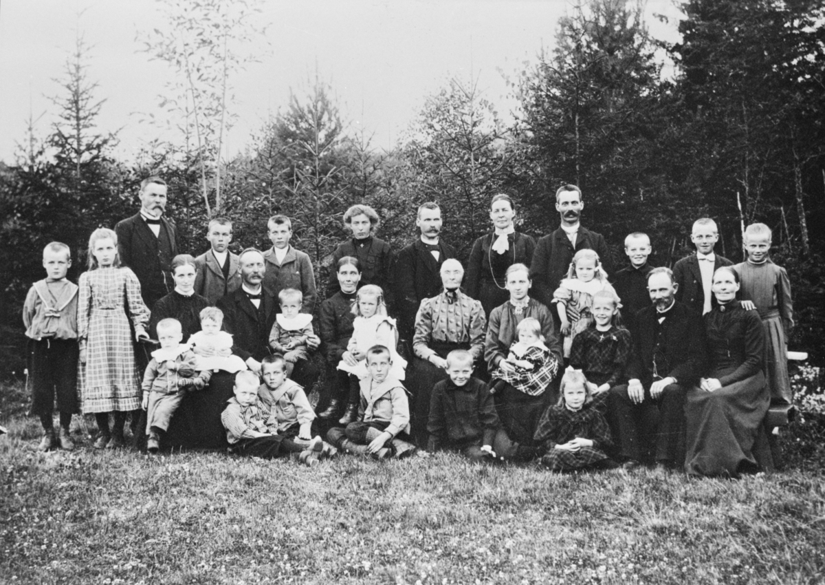 Oppland, Øyer, familien til Guri Opjordsmoen, som sitter midt på bildet.
De øvrige personene på bildet er navngitt i katalogen.