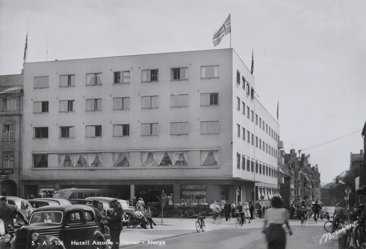 Postkort, Hamar, Østre Torg, Vangsvegen, Torggata 23, Hotell Astoria, Esso Bensinstasjon og gullsmed på hjørnet av hotellet, en lastebil fra Hamar Bryggeri en Dodge 1937-38 modell, i forgrunnen en Ford junior de Luxe 1936-37 modell,