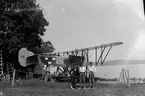 Flygplan FVM S 21 nummer 4214 står uppställd på en vagn vid Roxens strand. Vid prov av flottörer 1924. Tre män står framför flygplanet.