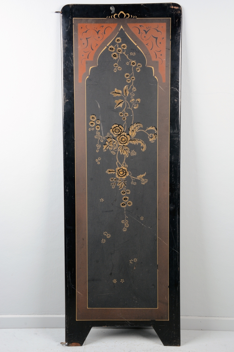 Svart skjermbrett av metall bestående av to paneler. Disse er dekorert med påmalt dekor i form av blomster i en ramme med løkformet overkant og med arabesker.