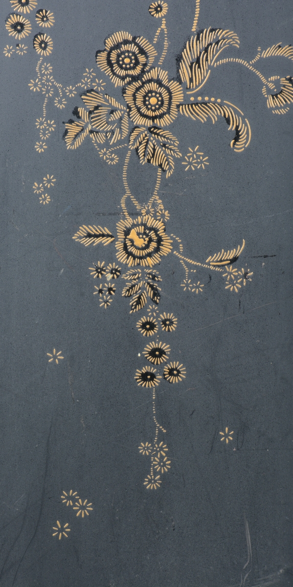 Svart skjermbrett av metall bestående av to paneler. Disse er dekorert med påmalt dekor i form av blomster i en ramme med løkformet overkant og med arabesker.